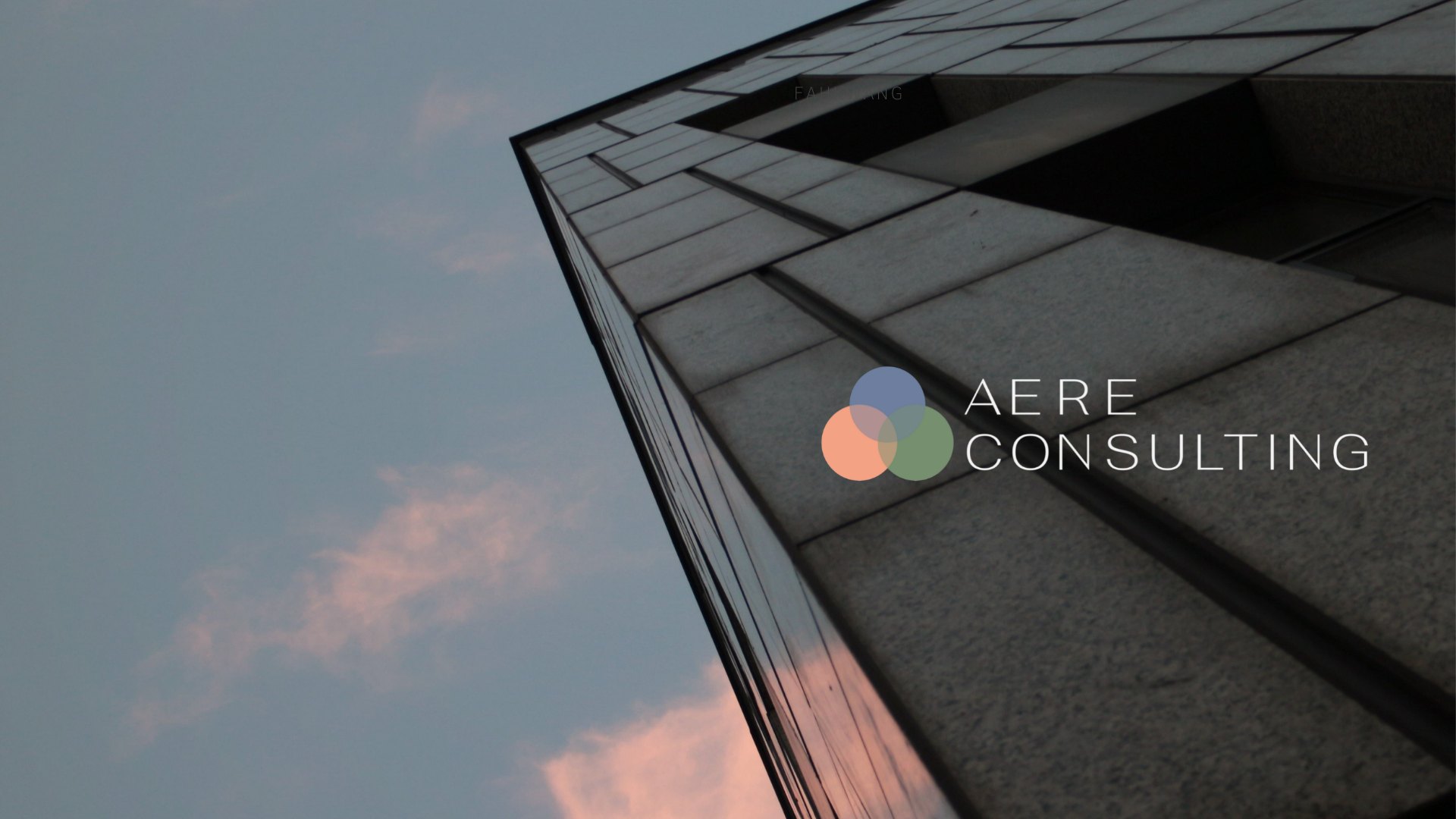 Looking up the corner of a stone office building at dusk, with the Aere Consulting logo
